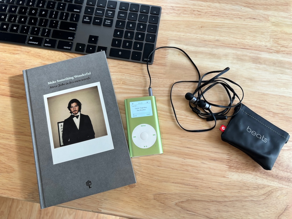 A photograph showing an iPod Mini playing Come Together by The Beatles, next to a copy of Make Something Wonderful: Steve Jobs in his own words.